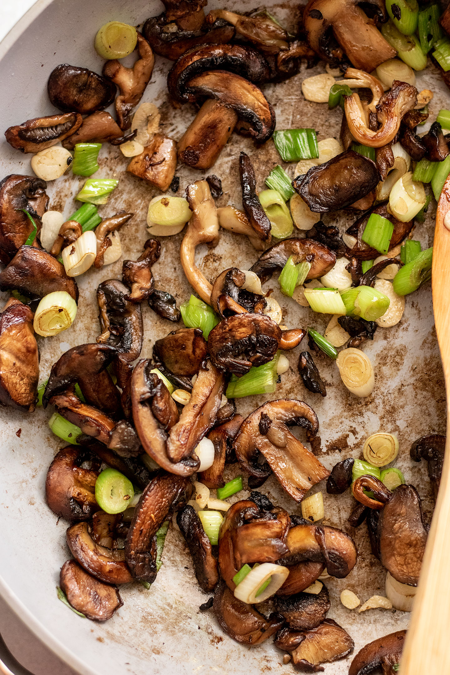Pan filled with pan-fried mushrooms, scallions and garlic slices.