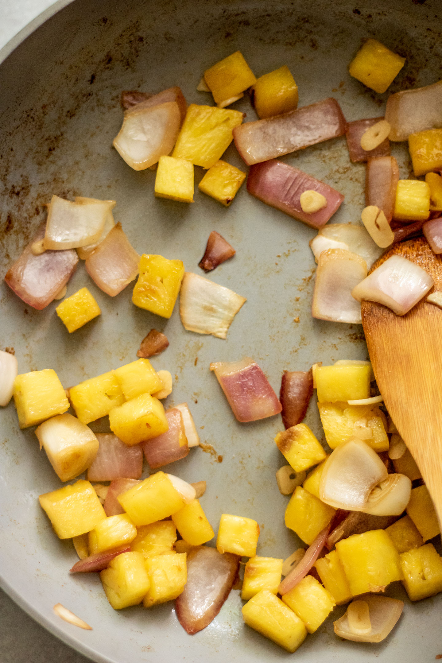 Satueing pineapple, garlic and onion together in a pan.