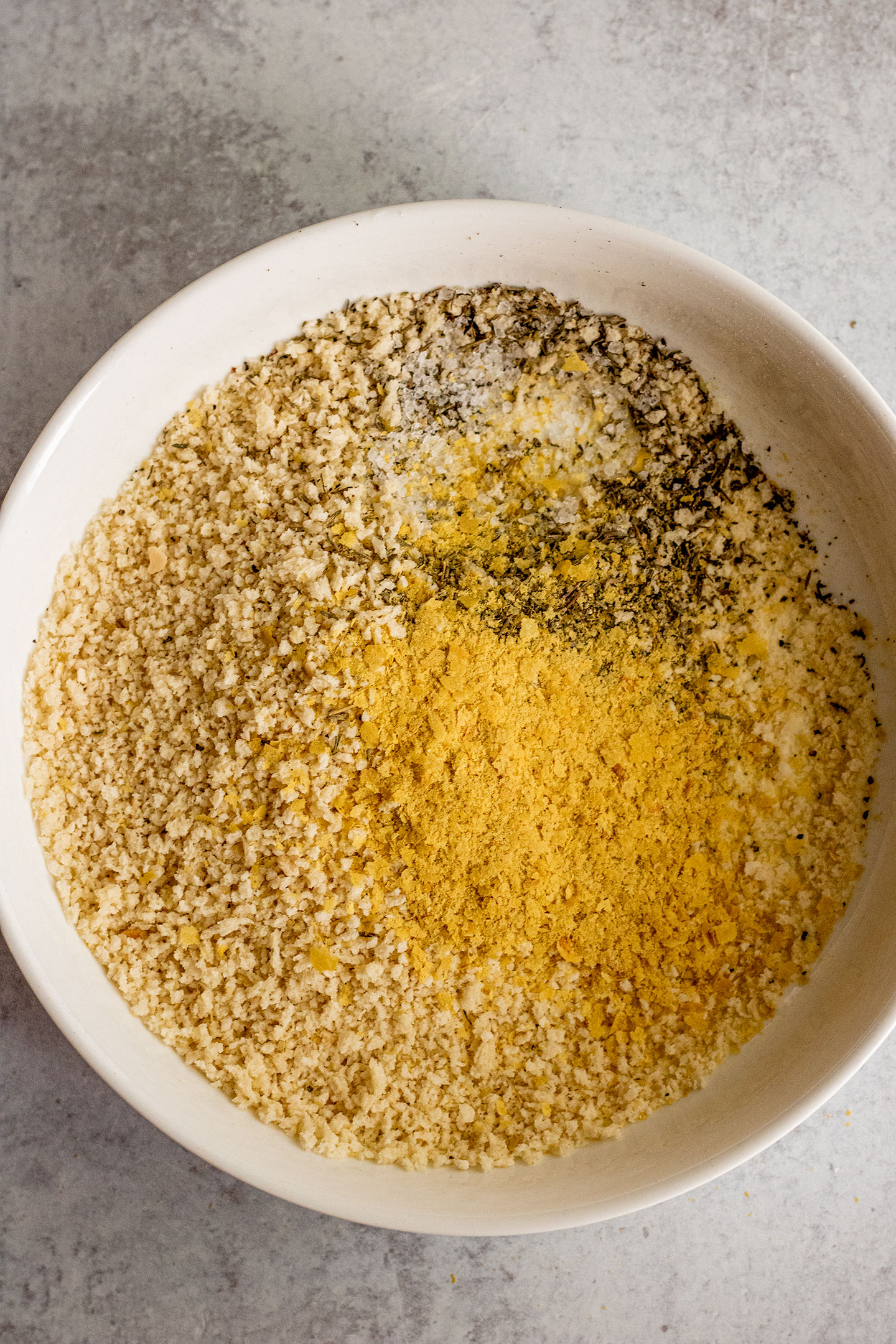 Panko mixed with nutritional yeast, herbs and salt and pepper in a bowl.