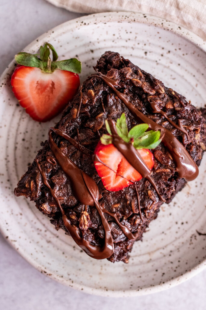 Top down view of chocolate baked oatmeal topped with strawberries and chocolate drizzle.