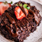 Close up of a slice of chocolate oats after baking in the oven, topped with strawberries and chocolate.