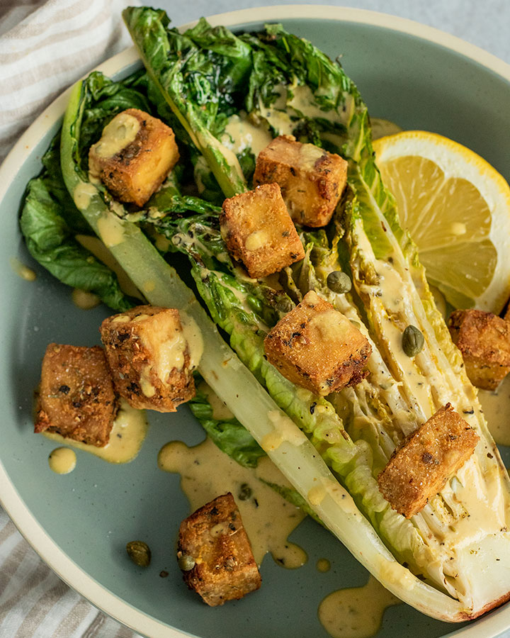 Grilled greens topped with crispy tofu croutons, dressing and served with a lemon wedge.