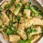 Close up view of a plate of pasta with basil, parsley and kale.