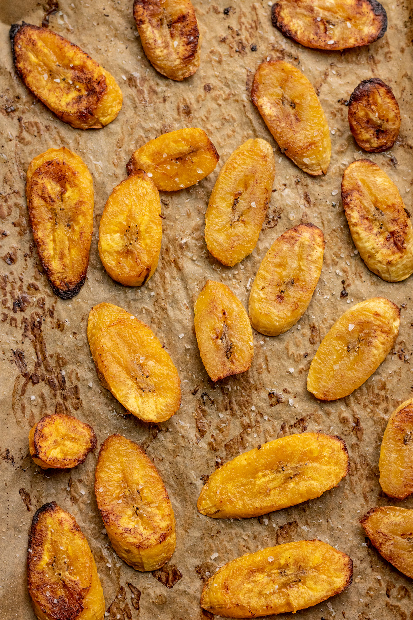 Baked plantain slices on a parchment lined baking tray.