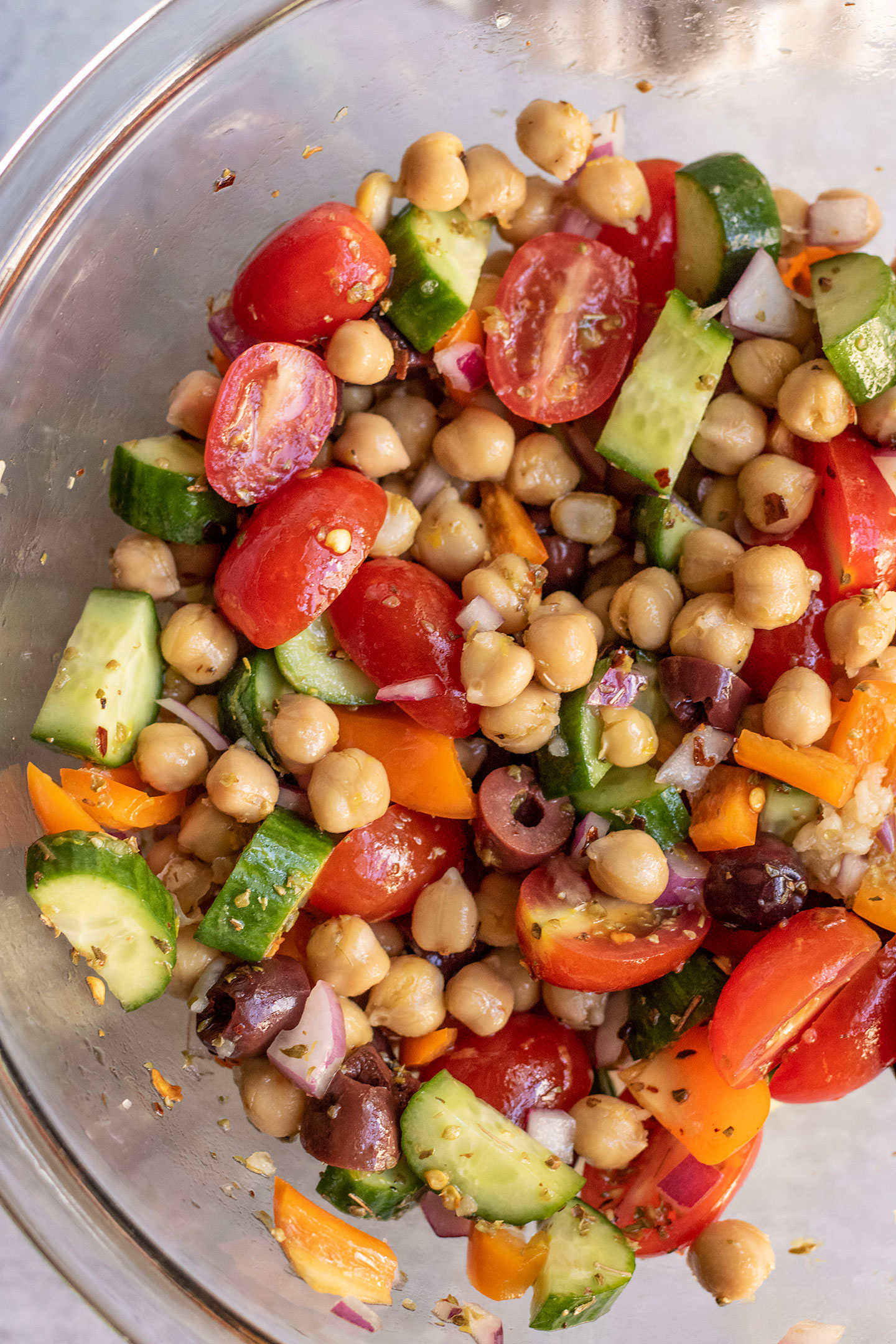 Mixing the chickpea salad together in a glass bowl.