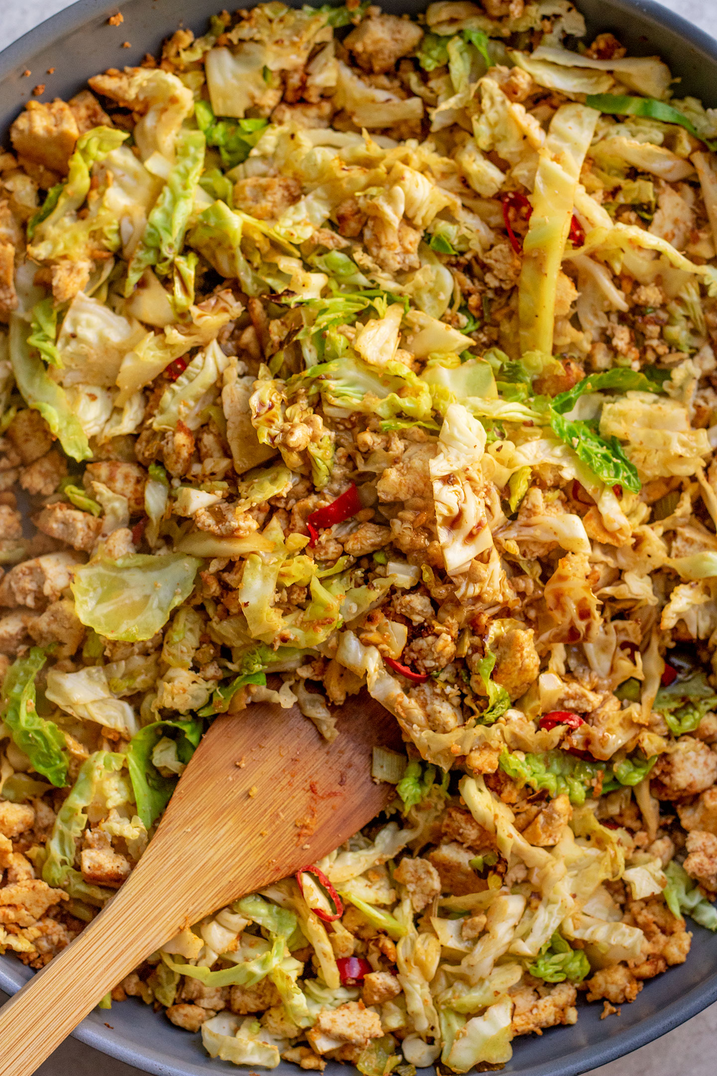 Stirring the cabbage into the tofu to cook.