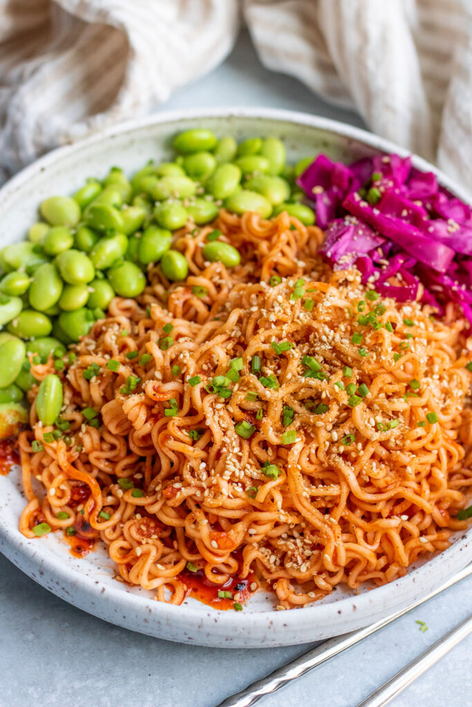 Gochujang noodles topped with crushed sesame seeds and chives served with edamame and pickled cabbage.