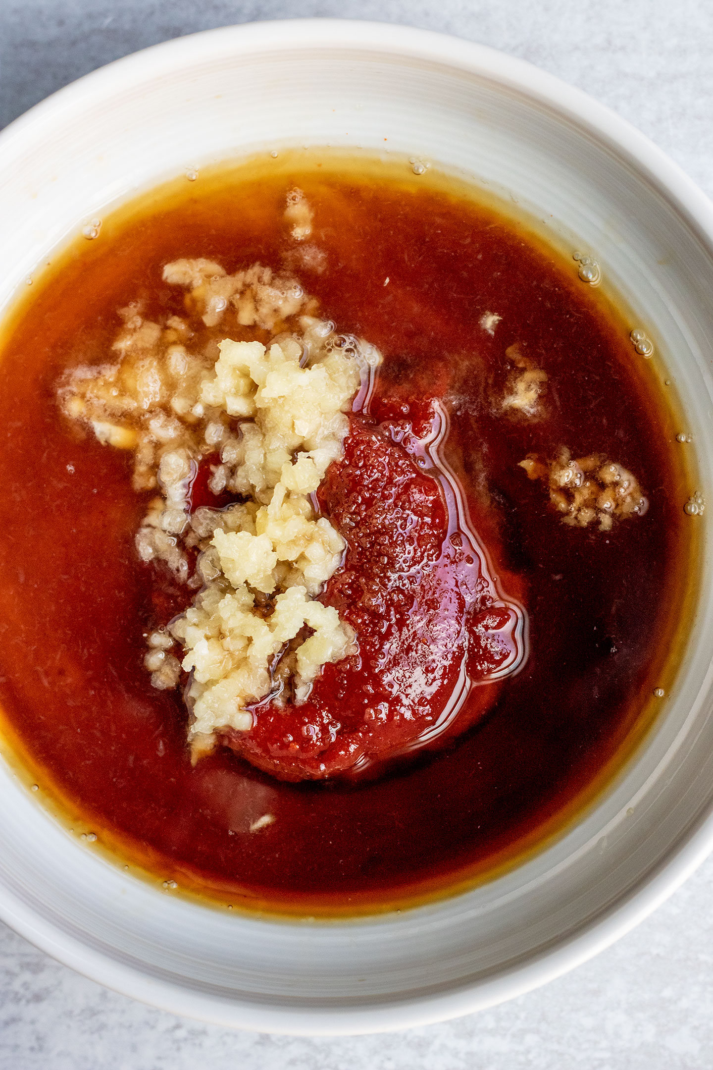 Placing the gochujang, soy sauce, garlic, sugar, maple syrup and rice vinegar together in a bowl to make a sauce.