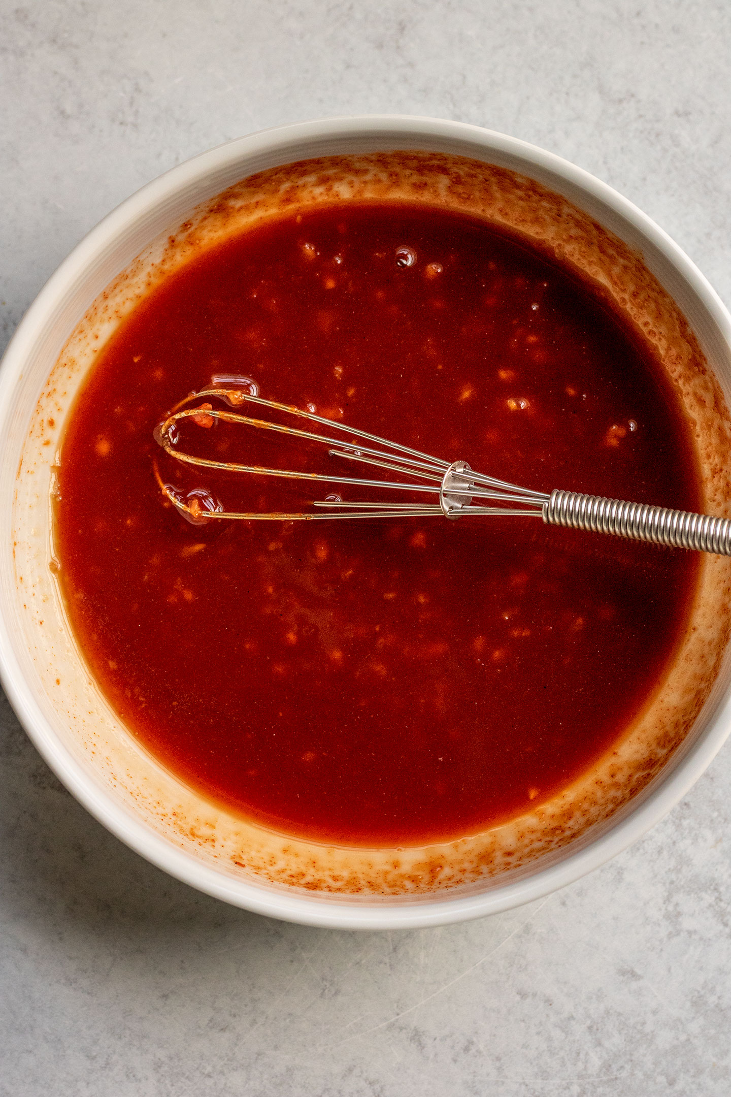 Mixing the gochujang sauce together in a bowl with a small whisk.