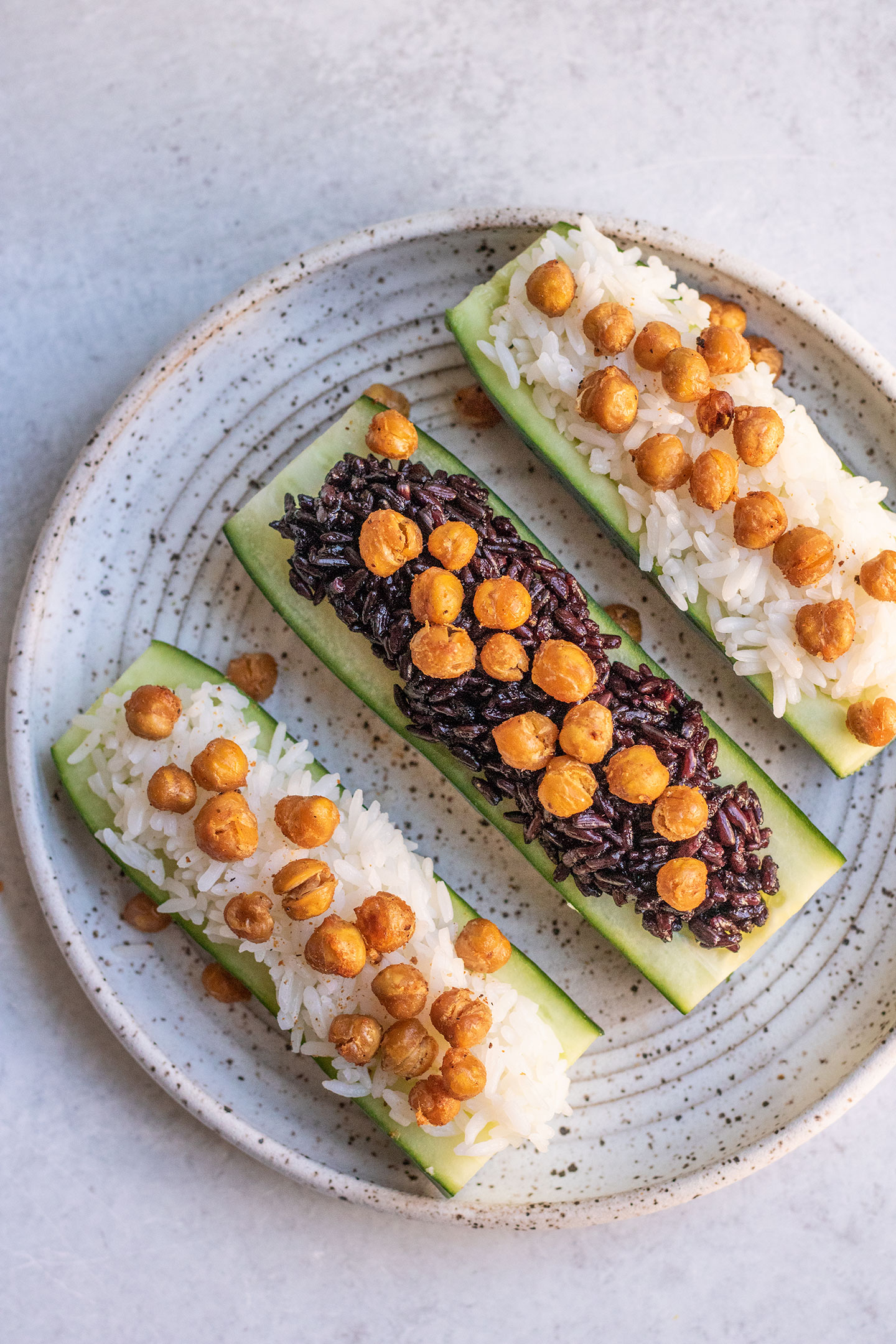 Plate with 3 rice stuffed cucumber boats topped with roasted chickpeas.