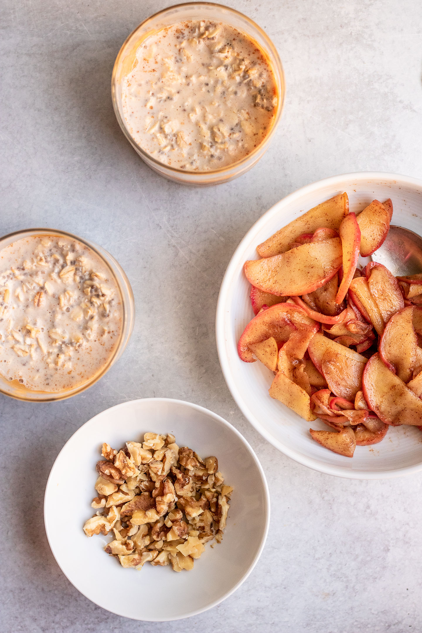 The overnight oats prepped in two jars with the sauteed apples and walnut toppings set to the side.