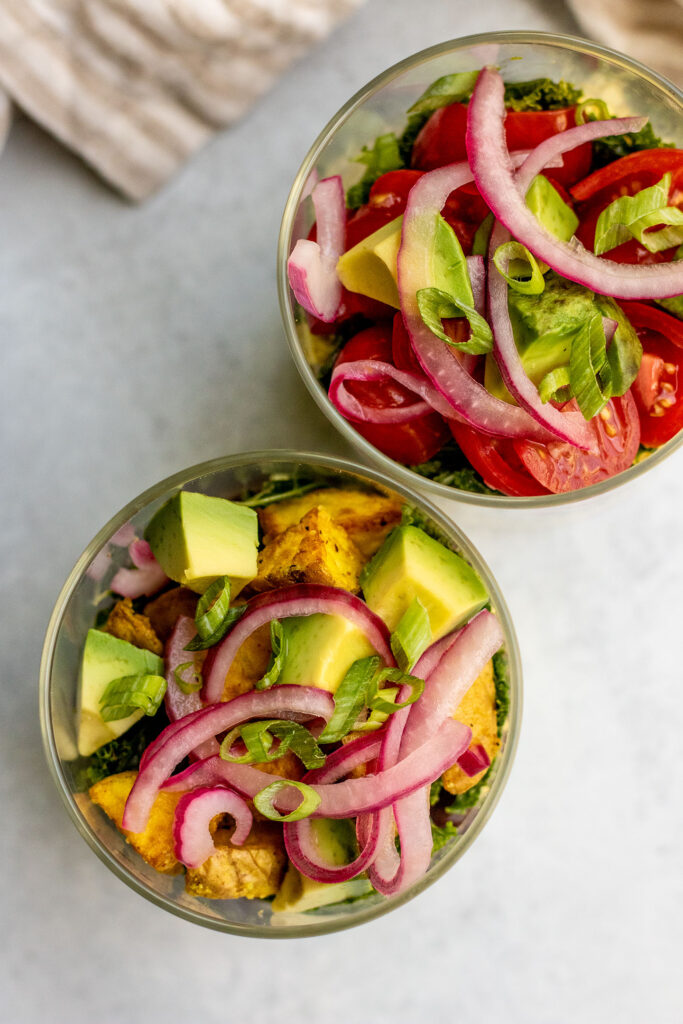 Top down view of two savory vegan breakfast jars topped with avocado and pickled onions.