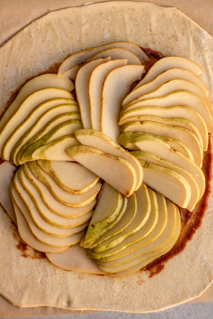 Layering the sliced pears on top of the puff pastry.