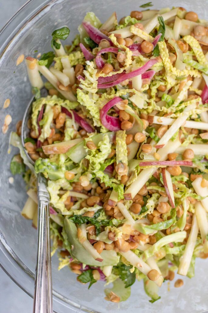 Lentil apple slaw mixed together with the maple mustard dressing in a large bowl.
