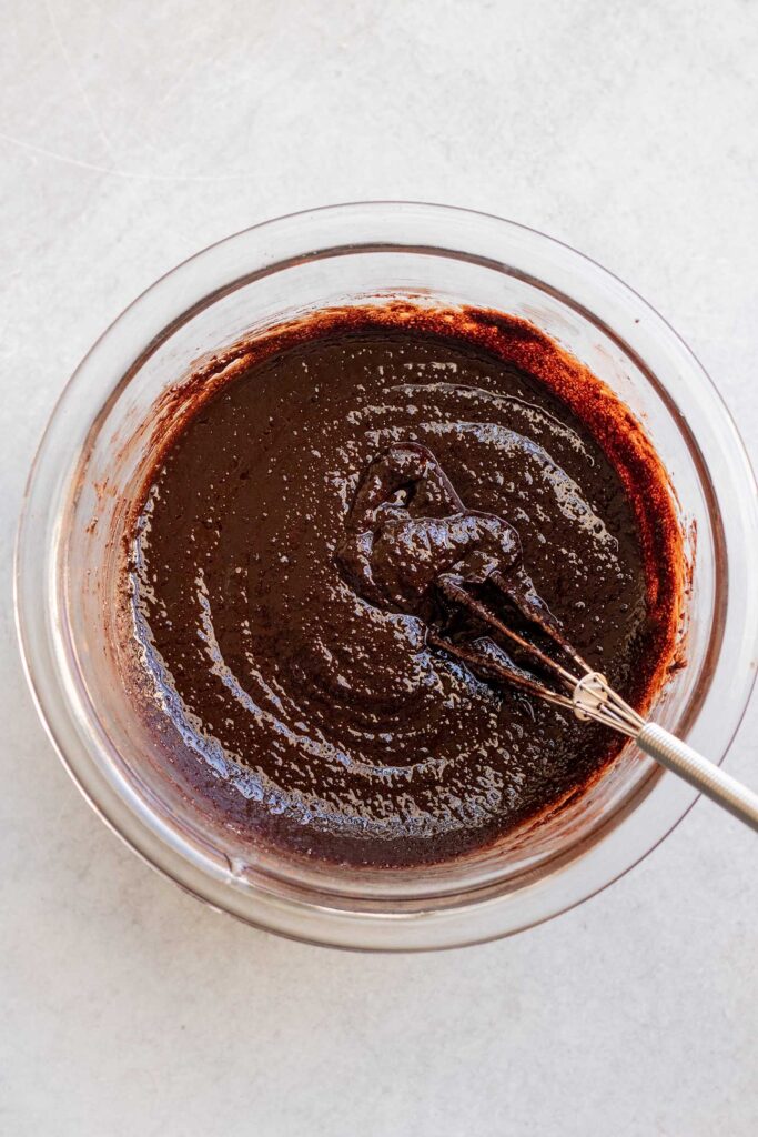 Mixing butter, sugar, melted chocolate, and cocoa powder together in a bowl.