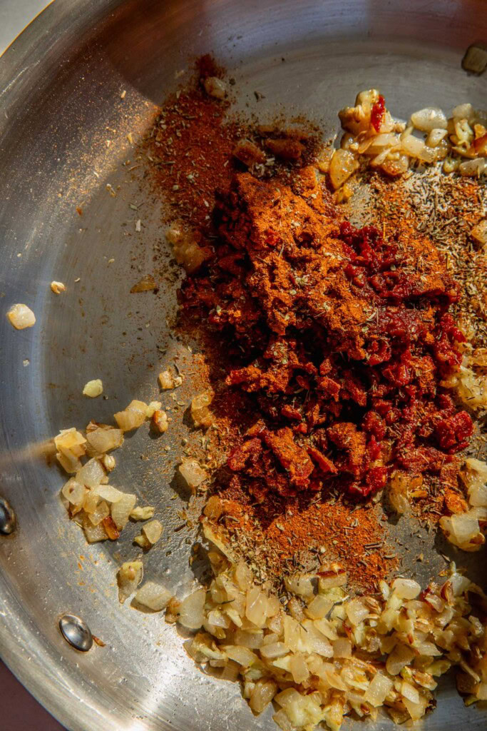 Adding the chipotle peppers, sun-dried tomatoes, and spices to the onions.