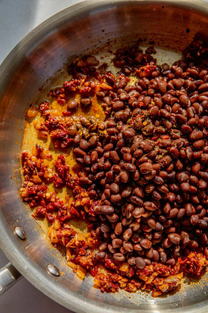 Adding the black beans and veggie broth to the pan.