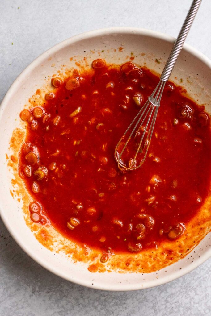Gochujang sauce whisked together in a white bowl.