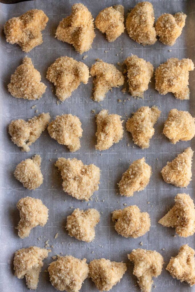 Cauliflower florets breaded with panko crumbs and placed on a baking sheet.