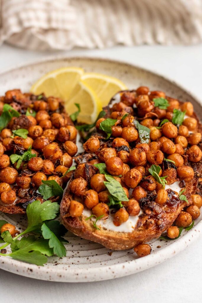 Two slices of toast spread with yogurt and spiced chickpeas.