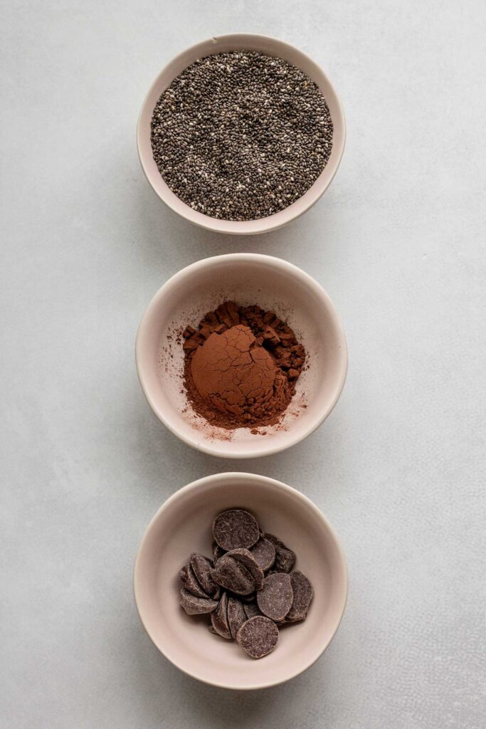 3 bowls filled with chia seeds, cocoa powder and chocolate chips.