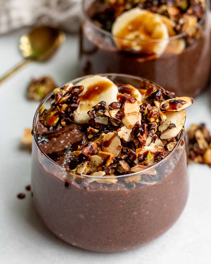 Close up of two cups of chia pudding topped with nutty granola.