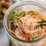 Close up of fully cooked instant noodles with fresh veggies in a jar.