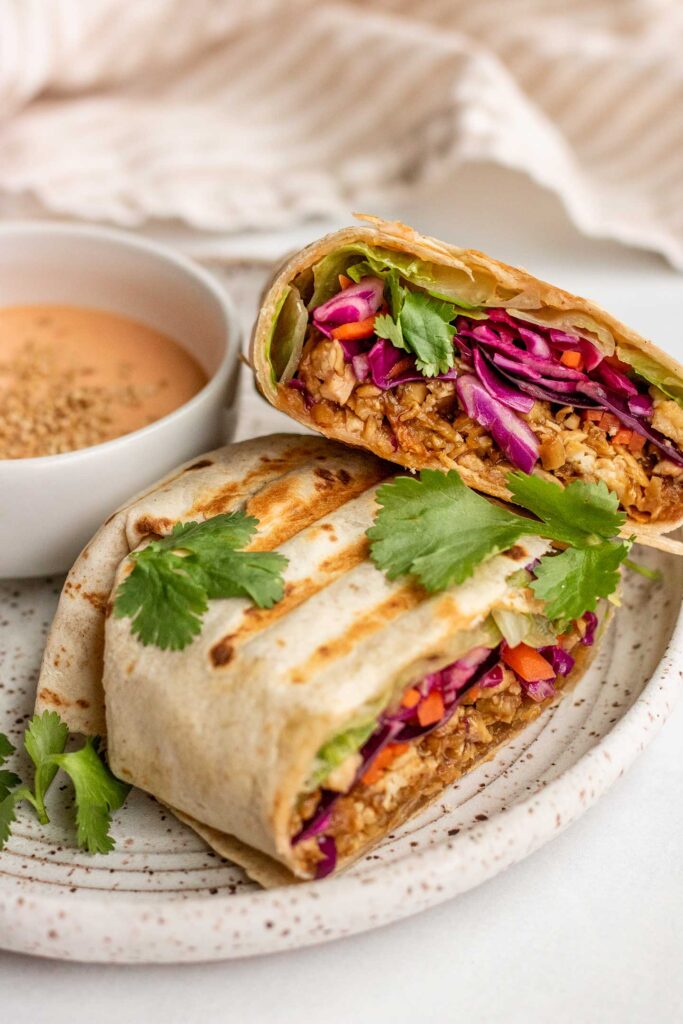 Close up of a plate of stacked toasted shredded tofu wraps.