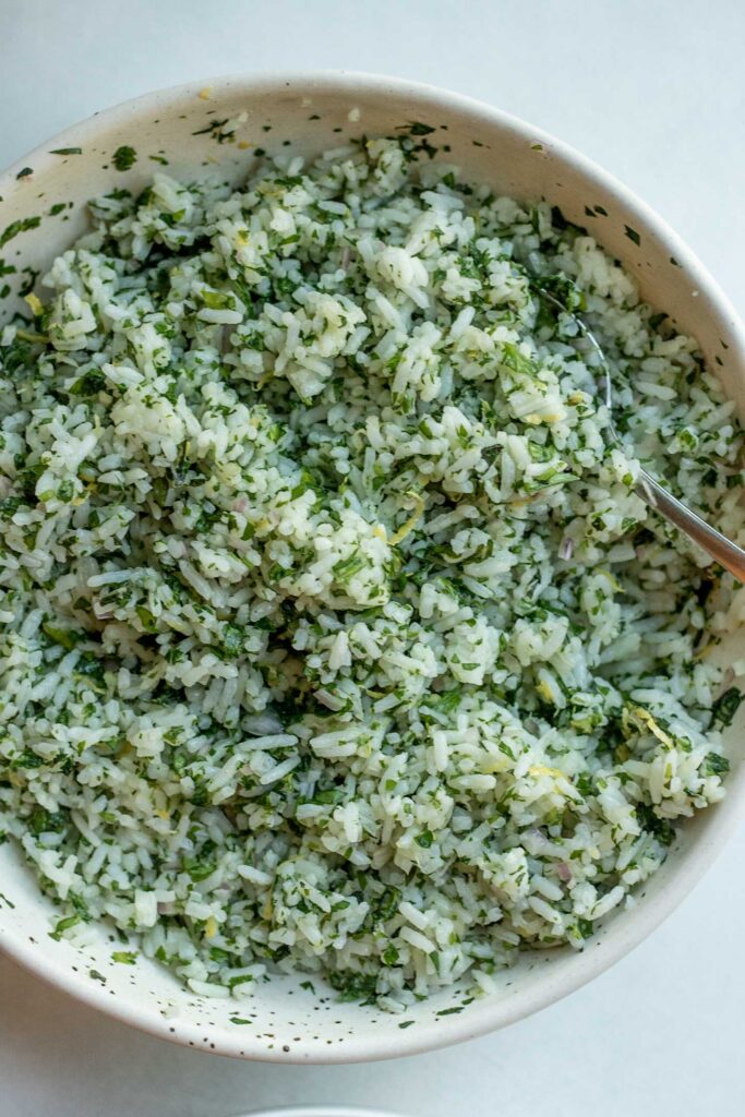 Rice fully mixed with minced herbs in a bowl.
