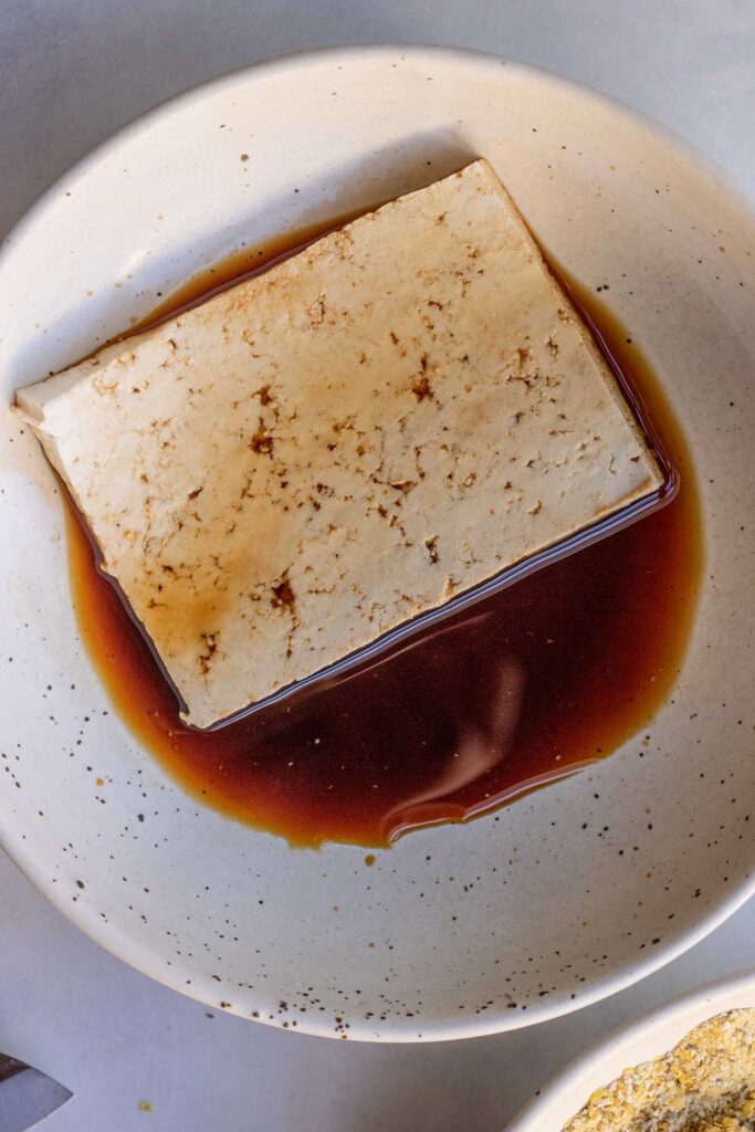 Coating a slice of tofu in some soy sauce.
