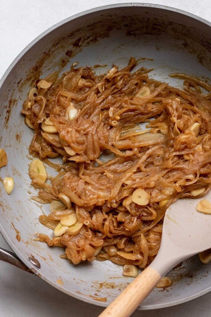 Stirring the jammy caramelized onions with the sliced garlic.