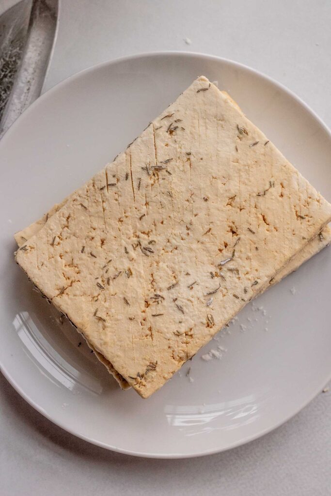 Tofu seasoned and dredged in cornstarch on a plate.