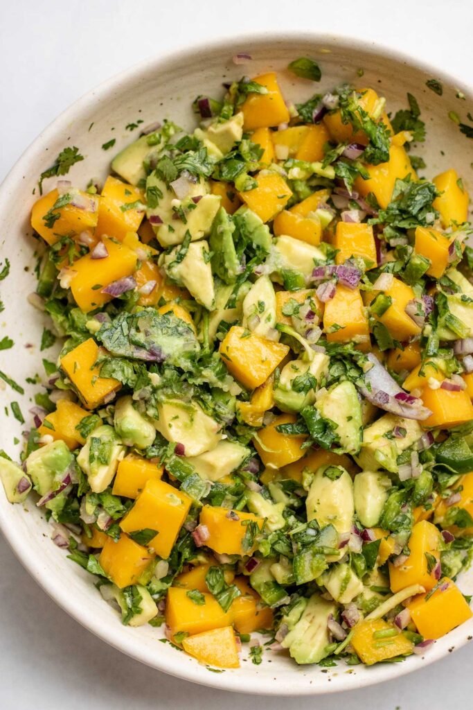 The mango avocado salad mixed together in a white bowl.