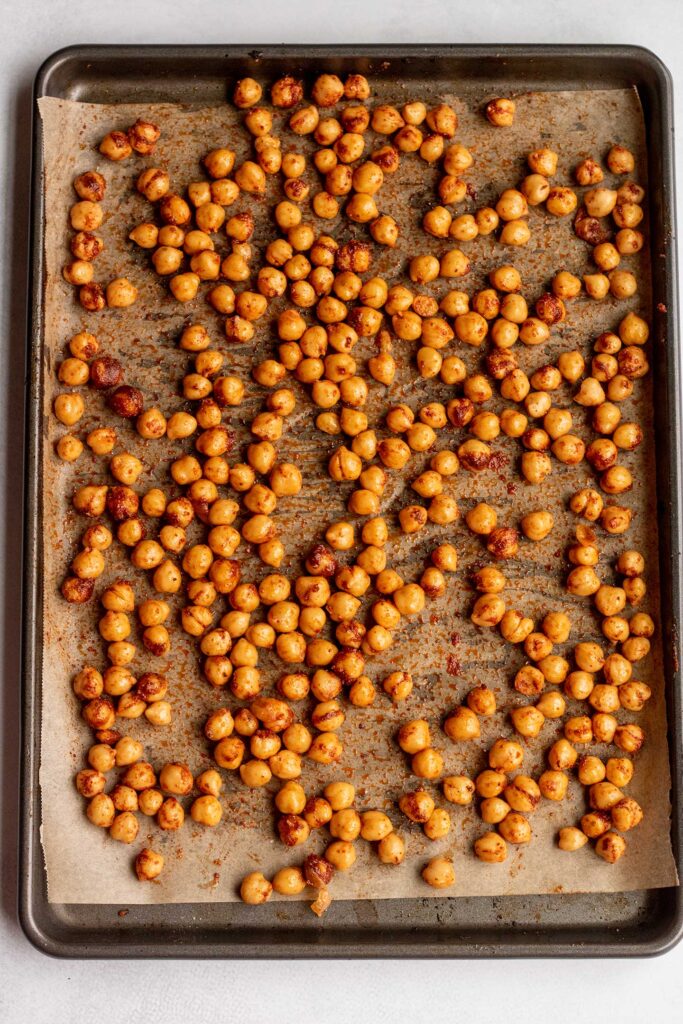 Chickpeas seasoned with smoked paprika and Old Bay Seasoning on a baking tray.