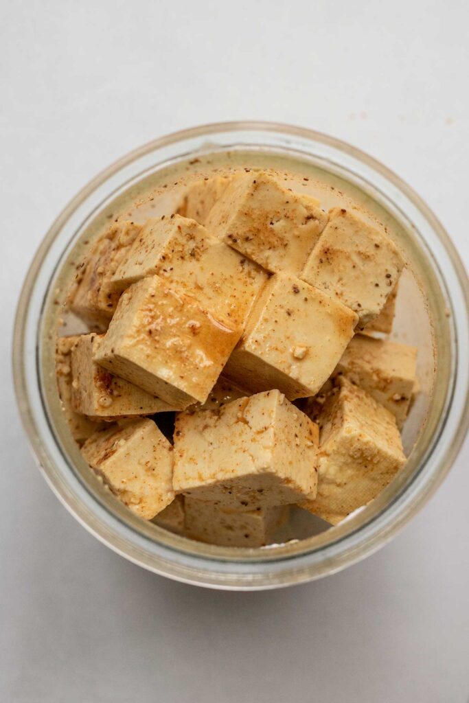 Seasoning the tofu cubes in a glass jar with old bay seasoning and cornstarch.