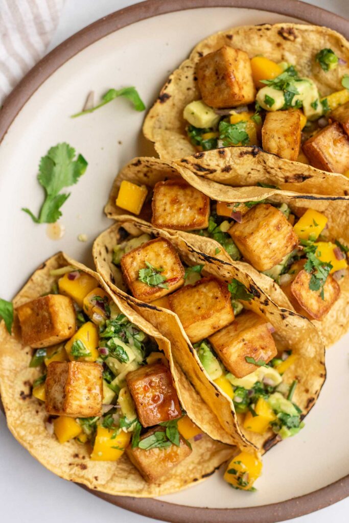 Four tortillas stuffed with mango avocado salsa and baked tofu.