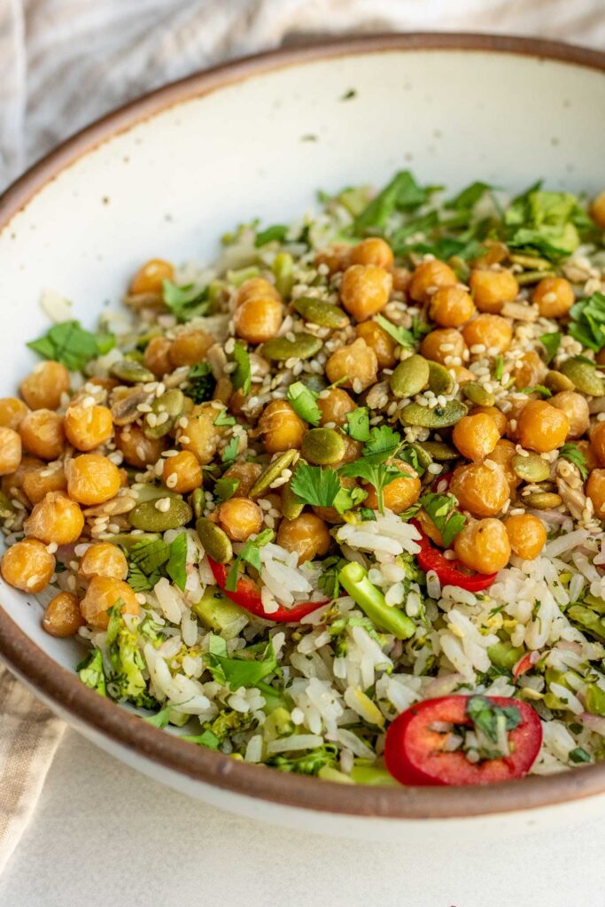 Side view of a bowl of broccoli rice salad topped with lemon chickpeas and cilantro.