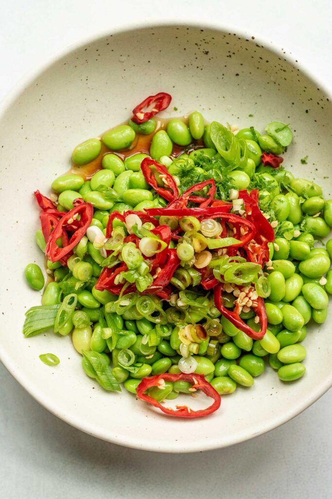 Bowl with edamame, fresno peppers, garlic, scallions, soy sauce and maple syrup.
