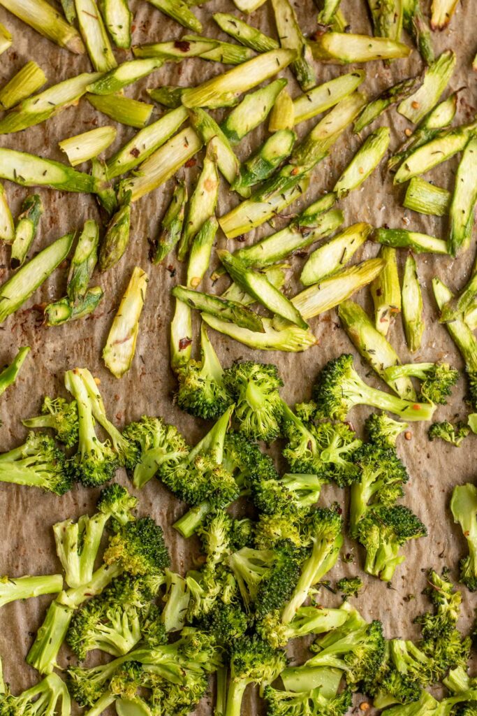 One side of a tray filled with roasted asparagus and the other side filled with roasted broccoli.