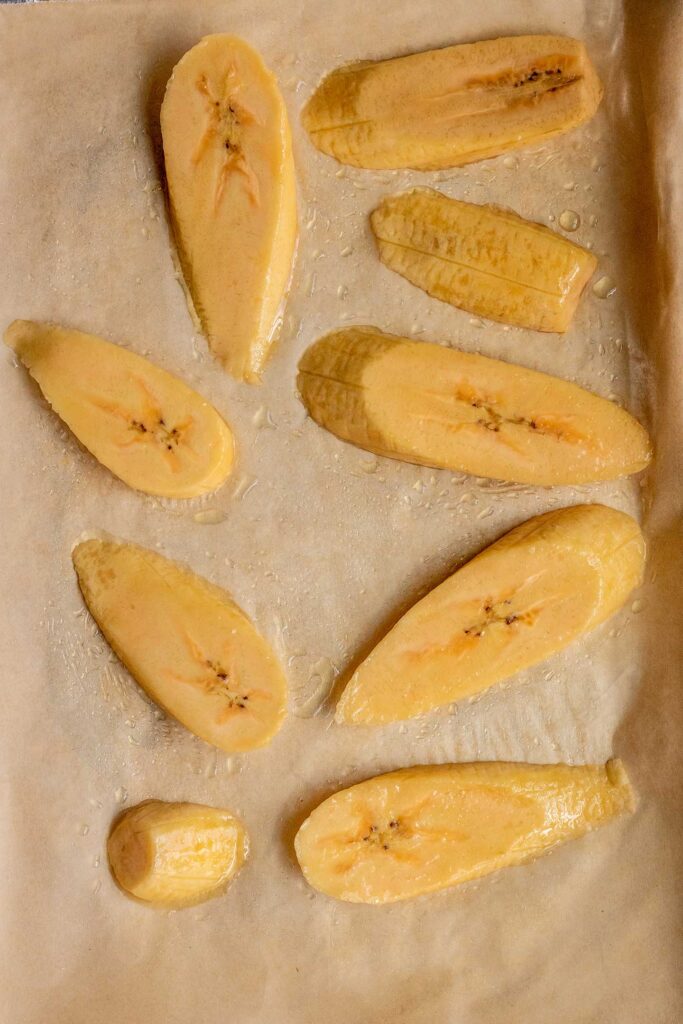 Sliced plantains on a baking tray ready to roast.