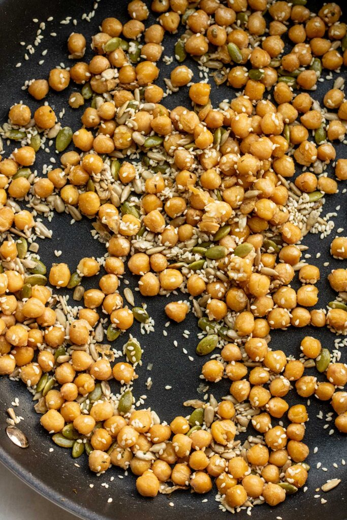 Chickpeas being toasted together and mixed with seeds, lemon and maple syrup.