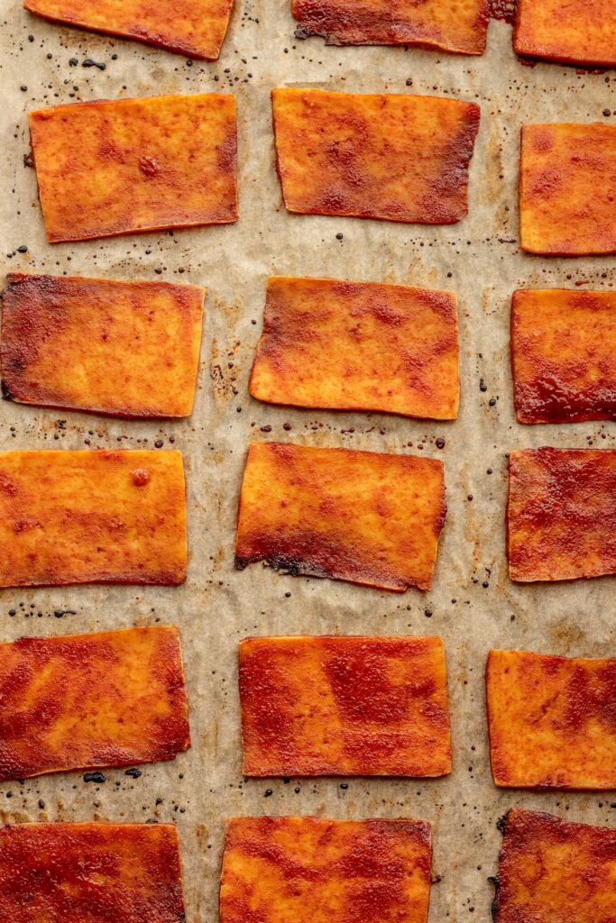 Baked marinated tofu slices on a baking sheet.