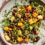 Serving bowl filled with coconut rice, black bean mango salsa and topped with pepitas.