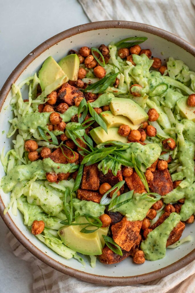 Top down of a bowl of cabbage slaw topped with crispy chickpeas, sweet potatoes and avocado slices.