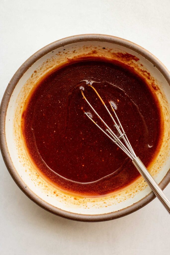 Whisking together to gochujang sauce in a small white bowl.