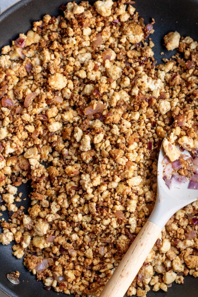 Seasoned tofu crumbles in a saute pan.