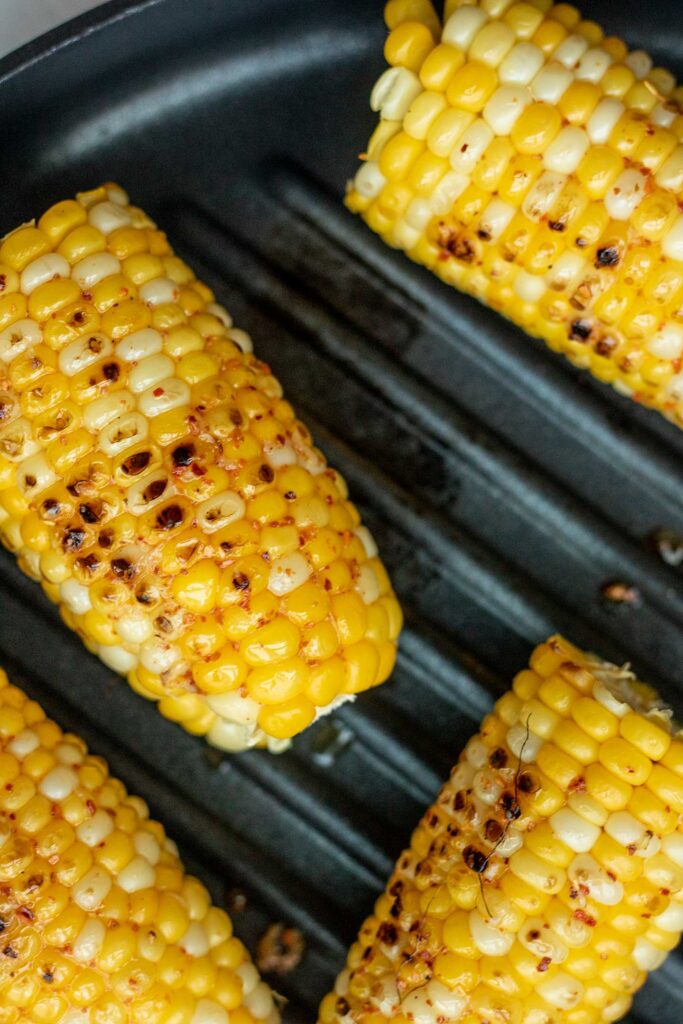 Corn placed on a grill pan to charge.
