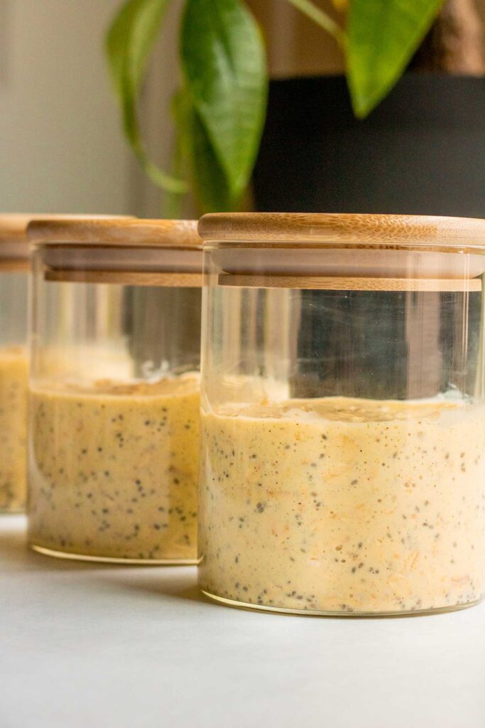 3 jars filled with rolled oats mixed with mango milk.