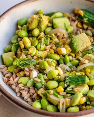 Tossing the farro and charred corn salad together in a bowl.