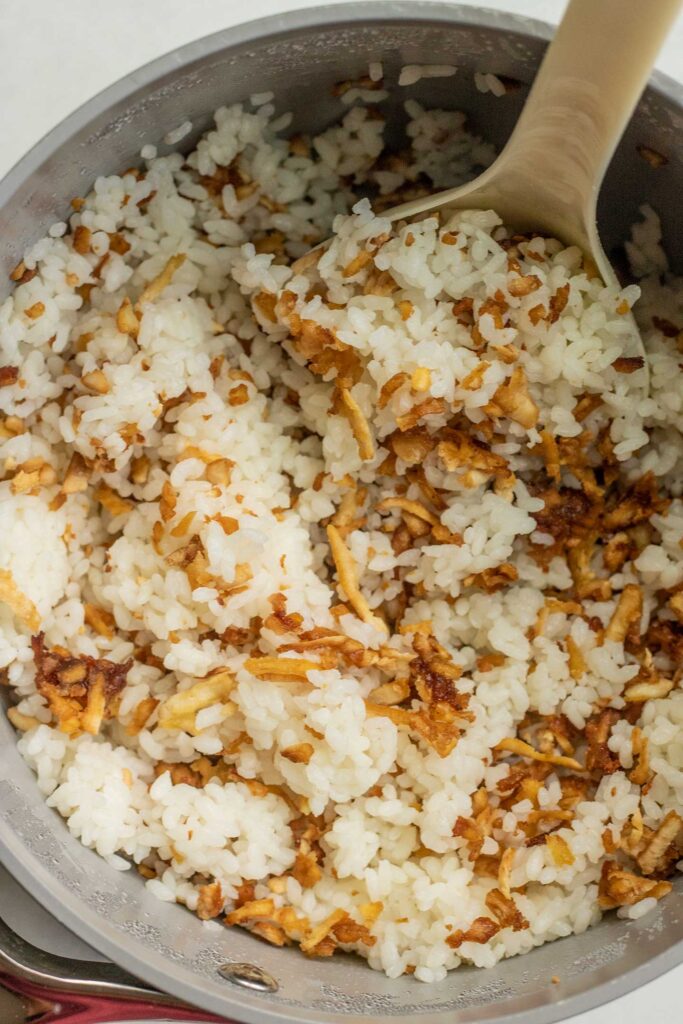 Mixing shredded tofu with rice in a pot.
